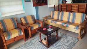 Un salon comprenant un canapé, deux fauteuils, une table basse et un tapis à motifs.