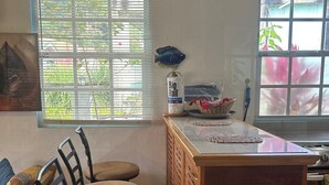 Una cocina con una isla de madera, taburetes de bar, un adorno de pez y una ventana con persianas.
