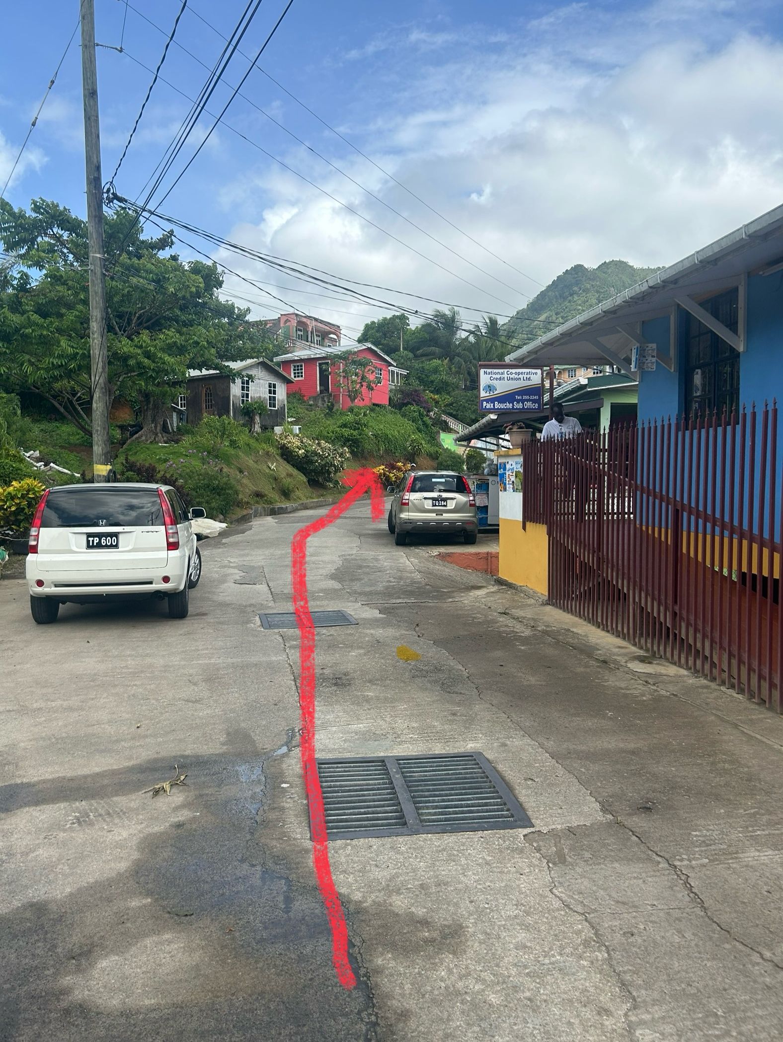 A street with a white car and a red arrow indicating a direction.