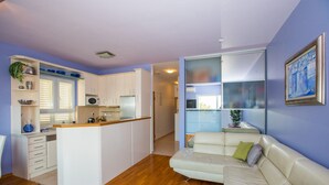 A modern apartment with a kitchen, a living area with a sofa, and a dining area. - Apartment 3 beaches with free parking (Dubrovnik)