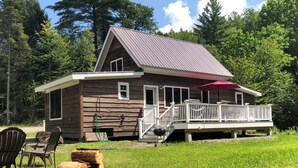 Une cabane rustique avec une façade en bois, un toit en métal et une terrasse dotée d’une rambarde.