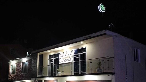 A two-story building with a sign reading "Hotel el Encanto."