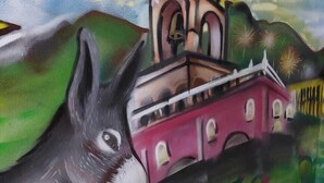 A donkey in front of a building with a bell tower.