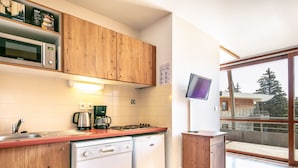A modern kitchen with wooden cabinets, a microwave, a coffee maker, and a dishwasher. - Appartement 6 pers proche pistes (Chamrousse)