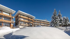 Ein Hotel mit mehreren Etagen, großen Fenstern und einer verschneiten Landschaft.
