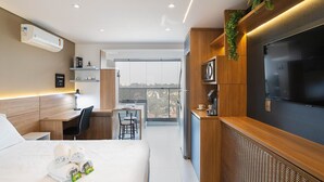 A modern hotel room with a bed, a desk, a TV, and a balcony with a city view. - Studio Lume 163 A (São Paulo)