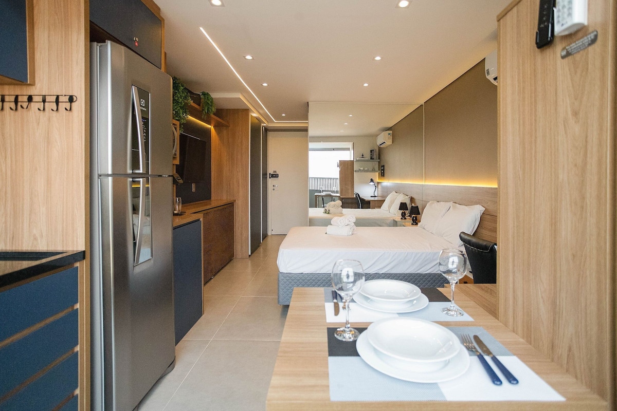Una habitación de hotel compacta con kitchenette, una cama con vistas y un comedor para dos.