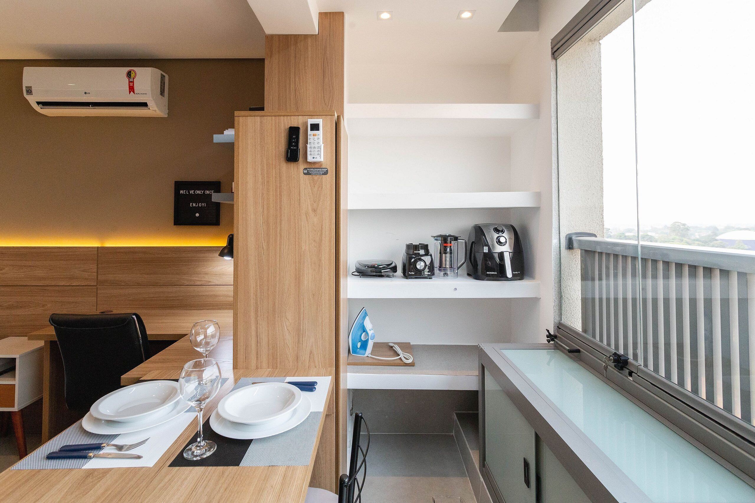 Habitación de hotel moderna con zona de comedor, kitchenette y balcón con vistas.