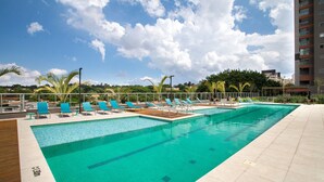 A swimming pool with blue chairs and a wooden deck. - Studio Lume 163 A (São Paulo)