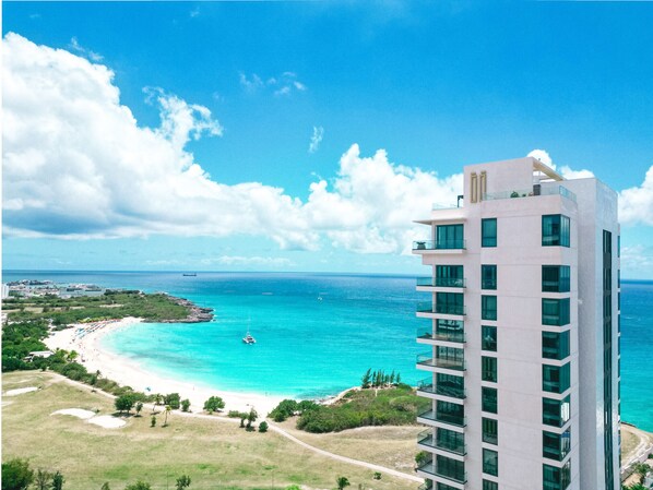 A high-rise hotel overlooking a turquoise beach with clear skies.