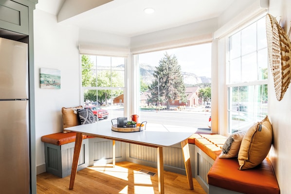 Een keuken met een inbouwkruk en een raam met uitzicht op een straat.