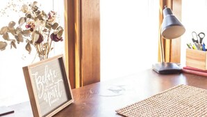Une table en bois, sur laquelle on a posé un panneau encadré, une lampe et un vase rempli de fleurs séchées.