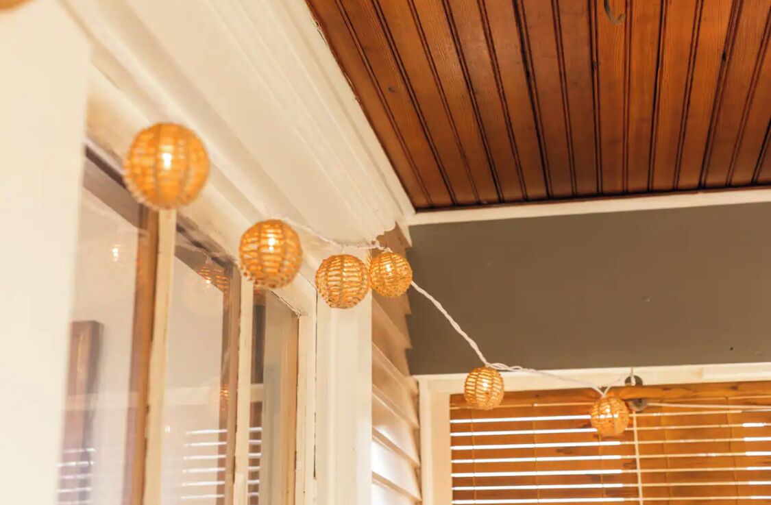Un plafond recouvert de lambris en bois et une guirlande de petites lampes sphériques décoratives.