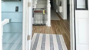Un escalier menant à un deuxième étage, dont l’extérieur est peint en bleu clair, avec une porte blanche et le numéro « 98 » inscrit sur le mur.