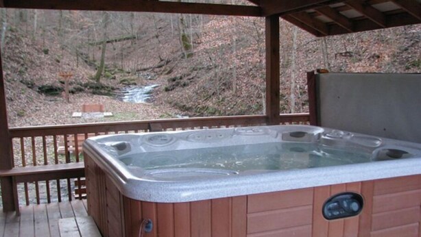 Ein Whirlpool mit einer Holzterrasse und Blick auf ein bewaldetes Gebiet.