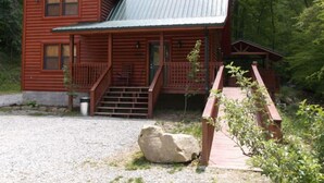 Eine zweistöckige Holzblockhütte mit Veranda und einer kleinen Treppe zum Eingang.
