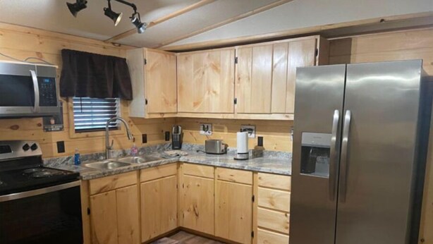 A compact kitchen with wooden cabinets, a stainless steel refrigerator, a microwave, and a stove. - 3BR, 2 Bath Cabin with full kitchen, living room, and hot tub. (Putney)
