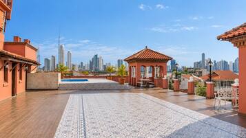 Eine Dachterrasse mit Pool, Sitzgelegenheit und Blick auf eine Stadtlandschaft.