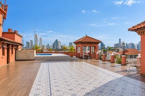 Une terrasse sur le toit avec une piscine, un espace salon et une vue sur les toits de la ville.