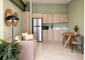 Un espace de vie compact comprenant un coin cuisine, un canapé, une table à manger et une plante en pot.