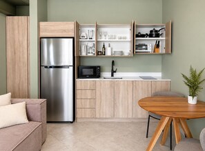 Une cuisine compacte équipée d’un réfrigérateur, d’un four à micro-ondes et d’une machine à café intégrés.