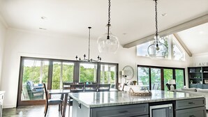 A spacious kitchen with a large island, dark cabinetry, and a built-in microwave.