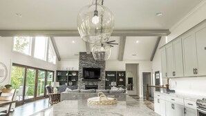 A spacious kitchen with a large island, a stone fireplace, and a dining area with a view.
