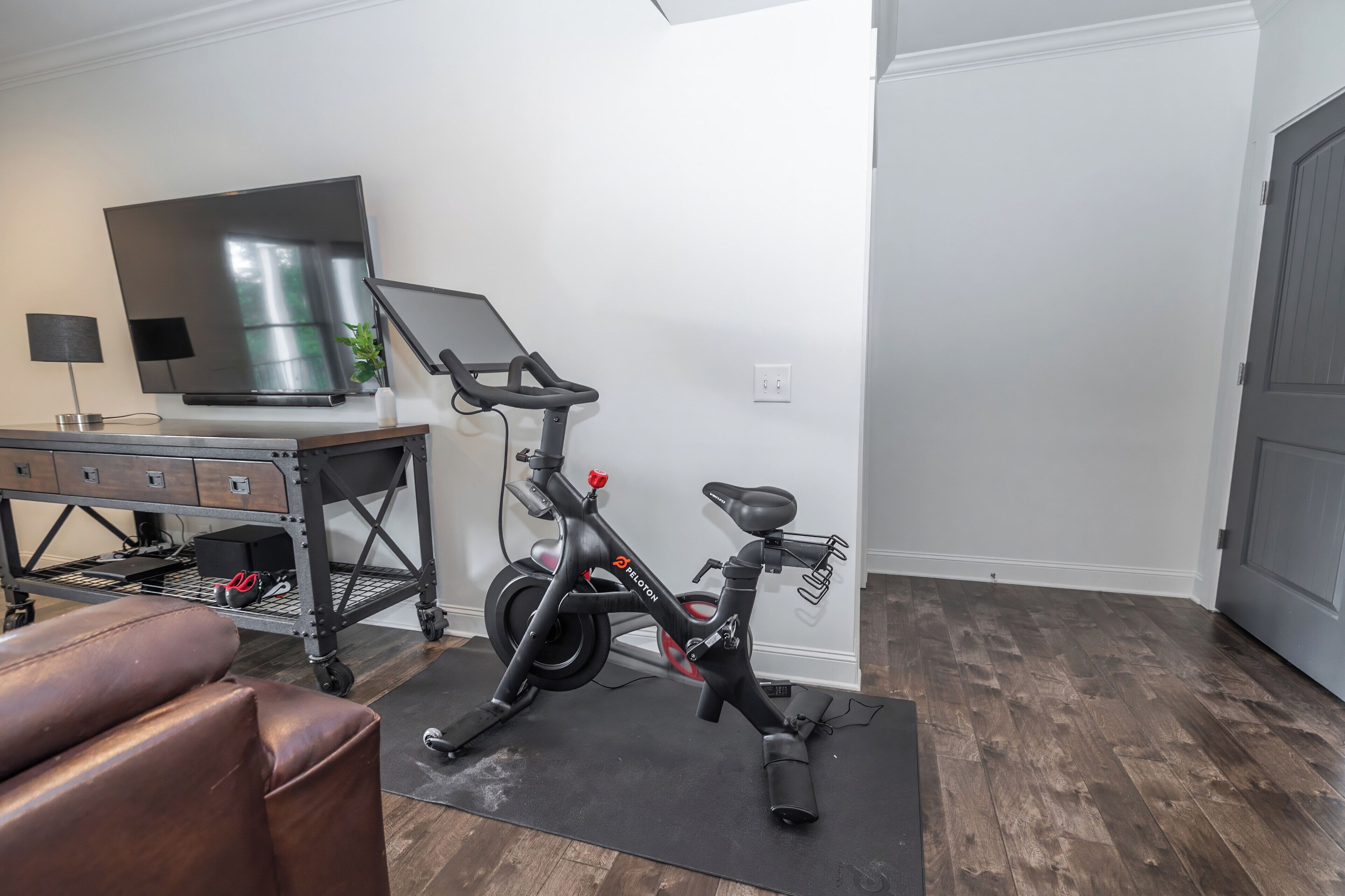 A home gym with a stationary bike, a treadmill, and a TV.