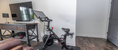 A home gym with a stationary bike, a treadmill, and a TV.