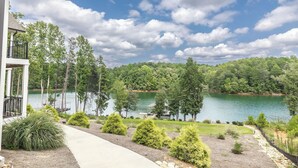 A lakeside property with a deck, a pathway, and a view of the lake and forest.
