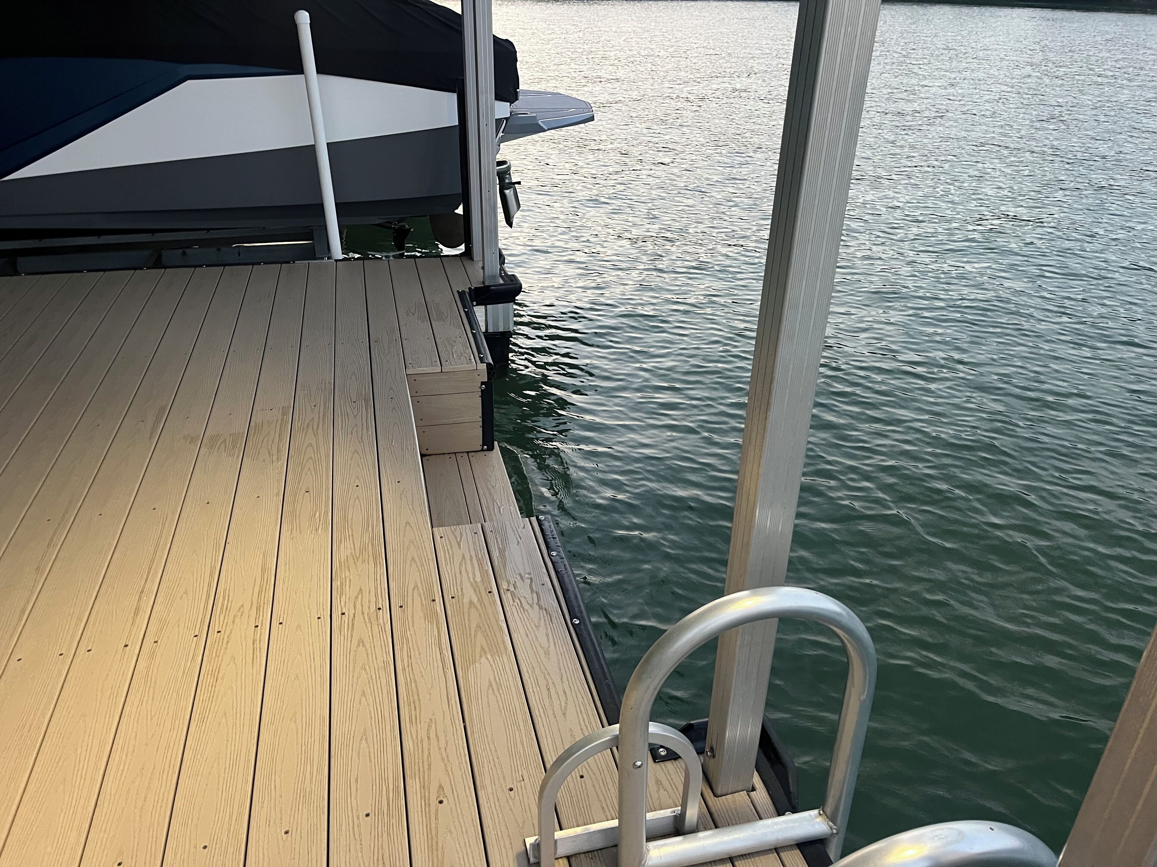 A wooden deck with metal railings and a boat docked at the edge.