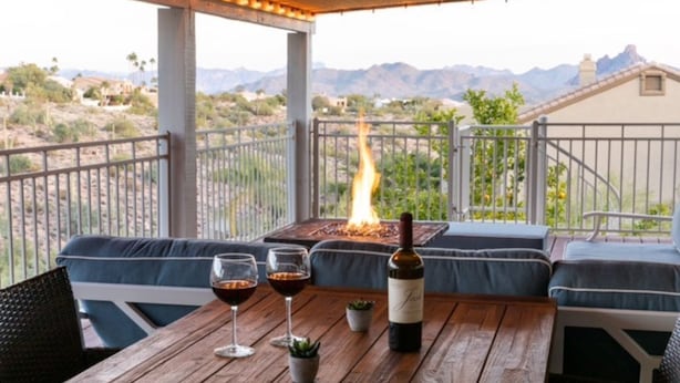 A wooden table with two wine glasses, a bottle of wine, and a small plant. - Beautiful views with a heated pool and plenty of room for large families! (Fountain Hills)