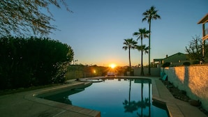 A swimming pool with a curved edge, surrounded by a stone wall and palm trees. - Beautiful views with a heated pool and plenty of room for large families! (Fountain Hills)