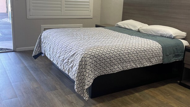 A bedroom with a bed, a window with blinds, and a door leading outside. - Town House Motel (Sanger)