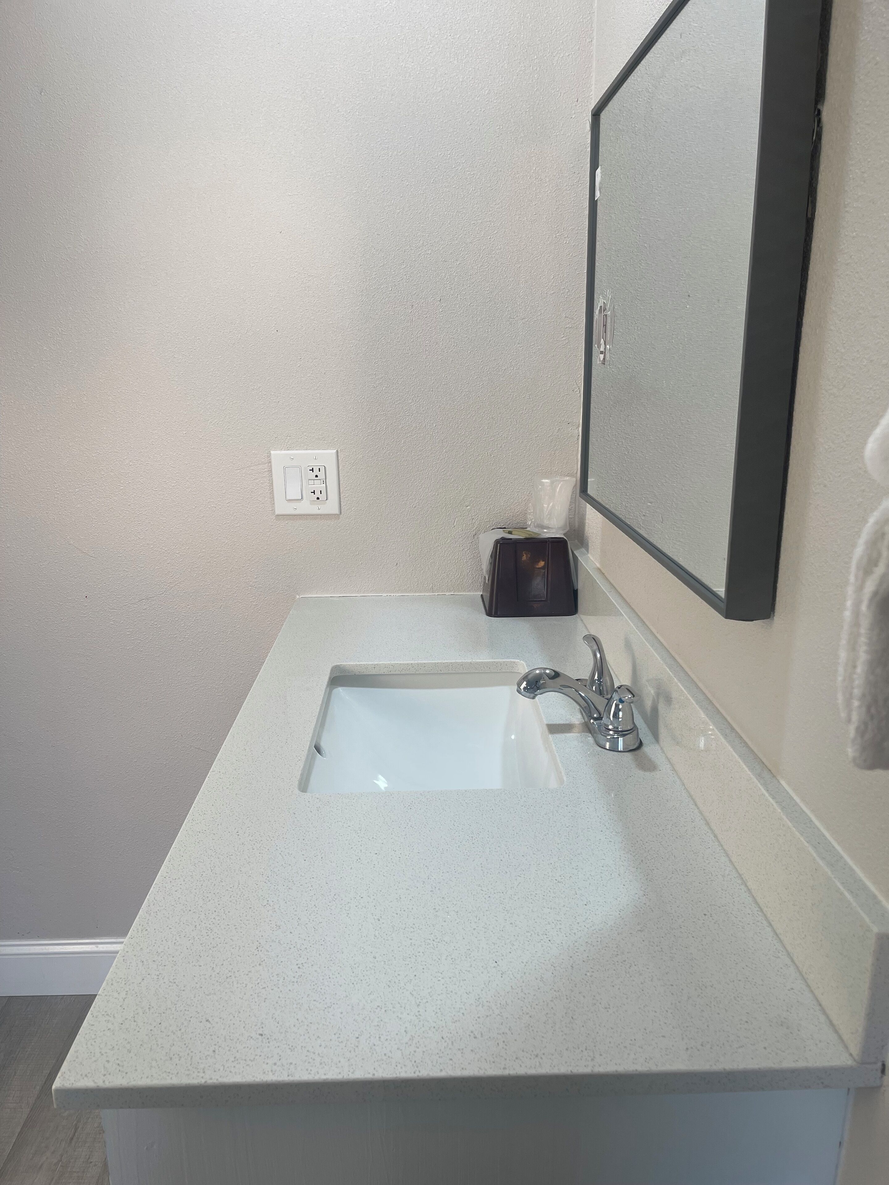 A bathroom with a white sink, a mirror, and a towel rack.