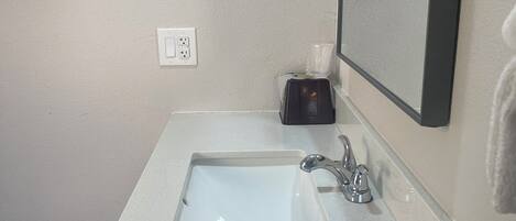 A bathroom with a white sink, a mirror, and a towel rack.