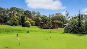 Golfkenttä, jossa on puinen mökki ja viheriöllä liehuva lippu.