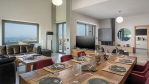 Un comedor moderno con una mesa de madera dispuesta para seis personas, un sofá de cuero y un televisor grande.