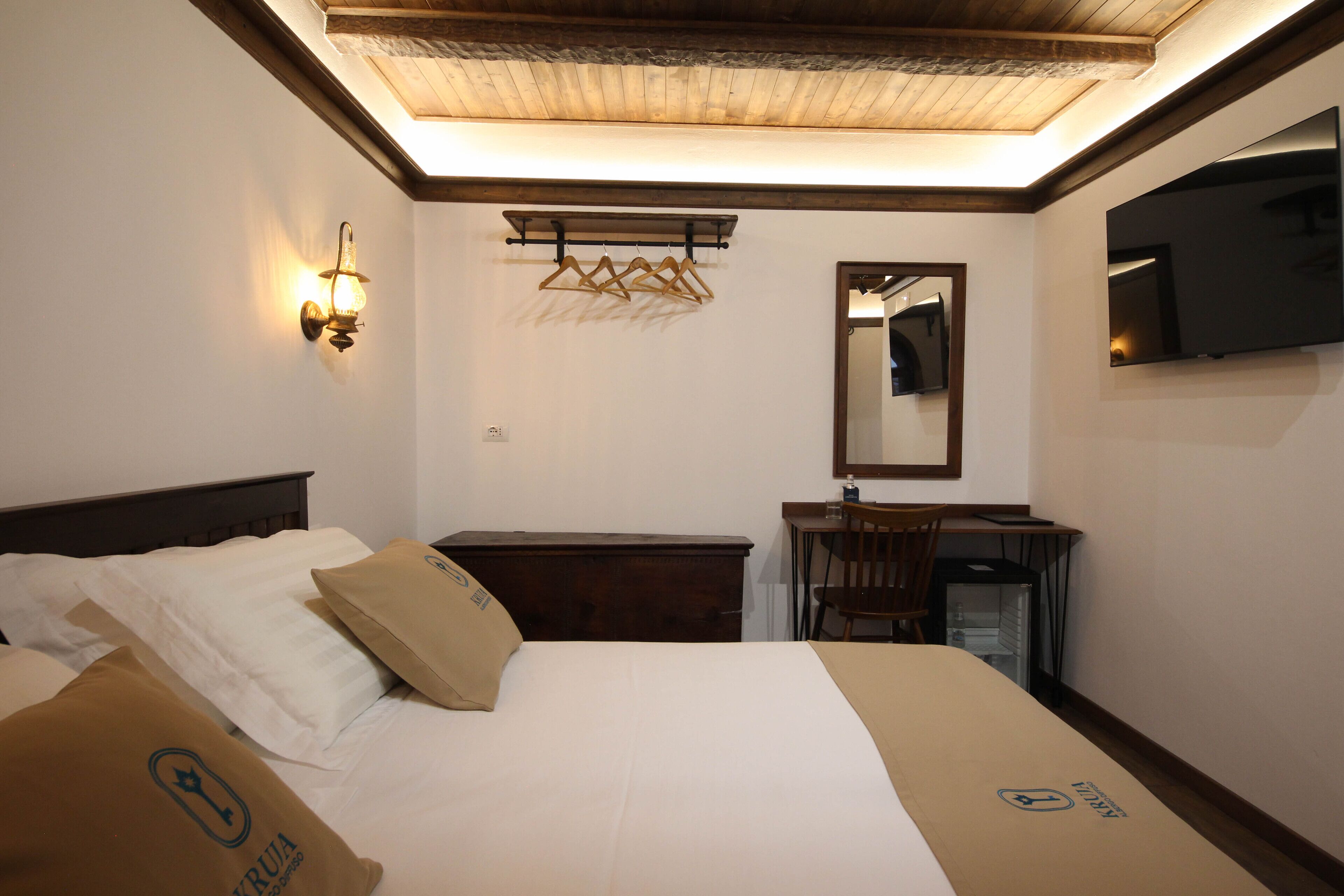 Een hotelkamer met een bed, een bureau, een stoel, een spiegel en een televisie.