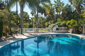 A swimming pool surrounded by palm trees and a white fence.