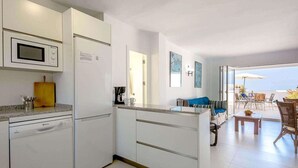A modern kitchen with a built-in microwave, a coffee maker, and a dining area with a view of the ocean. - Tetuan 17 - El Oasis de Capistrano! (Nerja)
