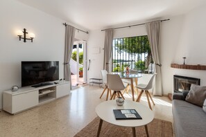 Una sala de estar moderna con televisor, sofá, mesa de comedor y sillas.