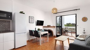 Un espace de vie compact comprenant une kitchenette, un coin repas et une cheminée.