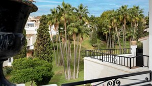 Un balcon avec vue sur des palmiers et un jardin bien entretenu.
