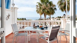 A terrace with a table set for breakfast, overlooking a coastal view with palm trees and houses. - Tetuan 11 - El Oasis de Capistrano! (Nerja)