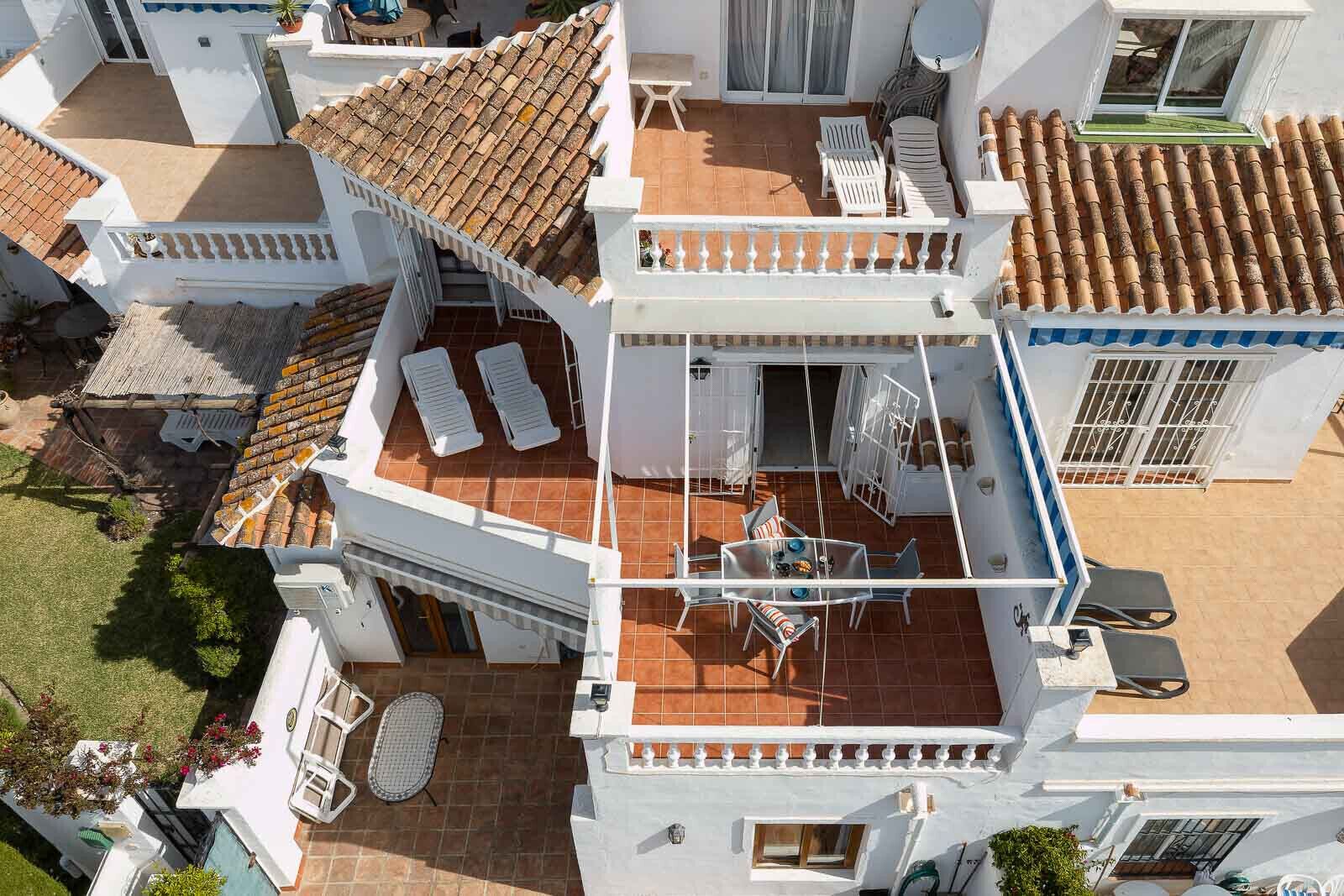 A rooftop terrace with a table and chairs, a pool, and a small garden area.