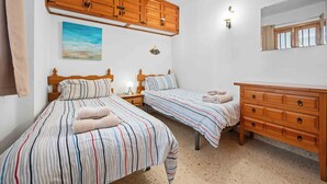 A bedroom with two beds, wooden cabinets, a painting, and a mirror. - Tetuan 11 - El Oasis de Capistrano! (Nerja)
