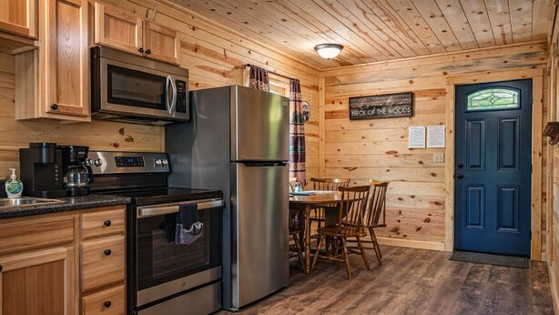 Une cuisine dotée de meubles en bois, d’appareils électroménagers en acier inoxydable et d’un coin repas avec des chaises.