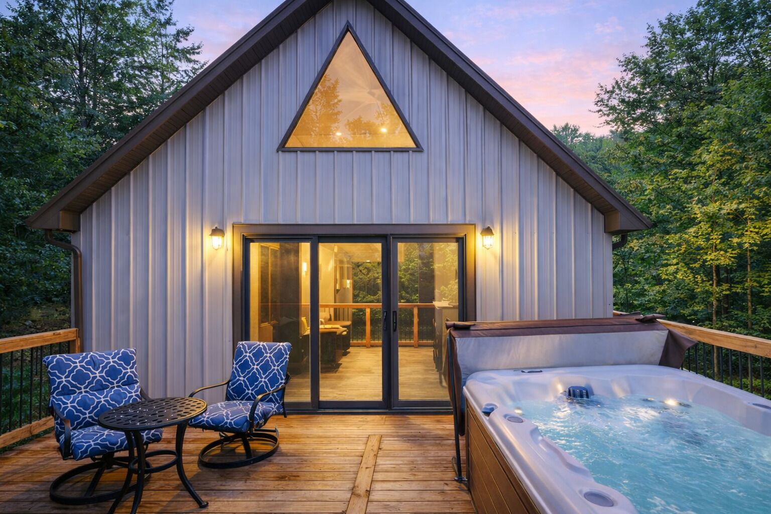 A modern cabin with a hot tub, wooden deck, and two rocking chairs.