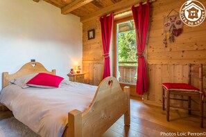 Cozy retreat with a single bed, wooden chair, and table, featuring a heart-shaped headboard and red accents.